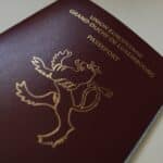 Close-up of a burgundy UK passport cover with a gold crest and partially visible 'UNITED KINGDOM OF GREAT BRITAIN AND NORTHERN IRELAND' text.