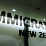 Glass wall with bold 'NEW ZEALAND' lettering reflected and partially cut off at the edges.
