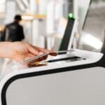 Hand swiping a card at a self-checkout kiosk in a store.