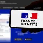 Close-up of a hand holding a smartphone displaying the France Identité digital ID card with the blue-white-red logo and silhouette profile on screen.