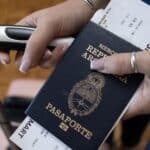 Hands holding a dark blue passport and boarding pass, ready for travel